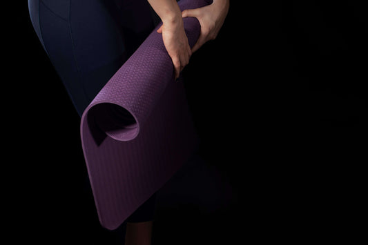 purple yoga mat with a non-slip textured surface being held for a supportive and comfortable workout. [ShopZip]